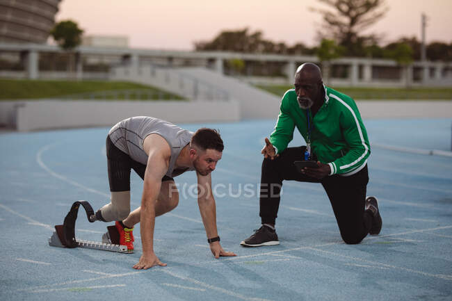 Кавказский спортсмен с протезной ногой в стартовой позиции для бега по трассе. Концепция паралимпийских игр — стоковое фото