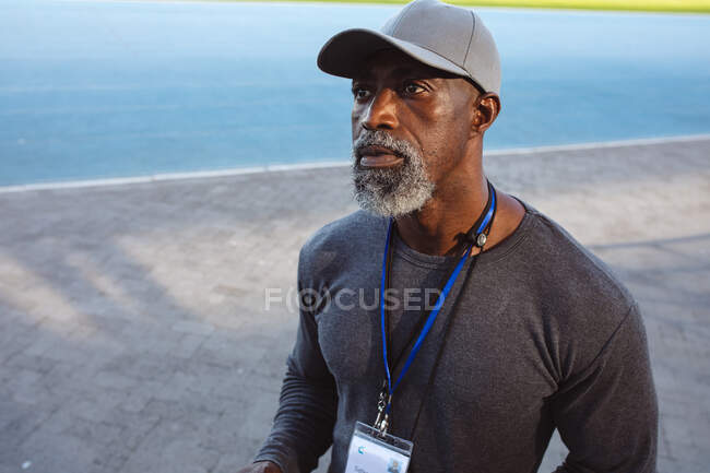 African american senior male coach wearing a cap standing in the stadium. paralympic sport concept — Stock Photo
