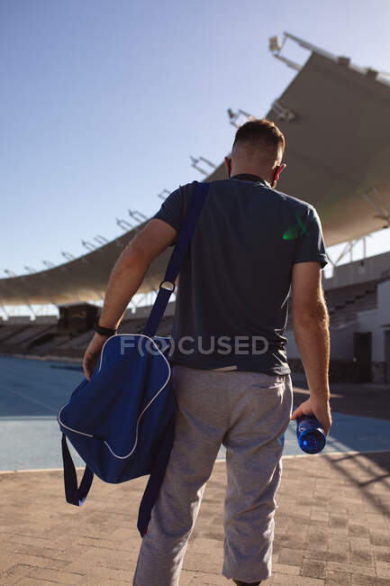 Visão traseira de atleta masculino caucasiano com perna protética em pé no campo esportivo. conceito de esporte paralímpico — Fotografia de Stock