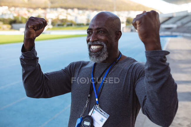 Щасливий афроамериканський старший тренер підбадьорює стоячи на стадіоні. паралімпійська спортивна концепція — стокове фото