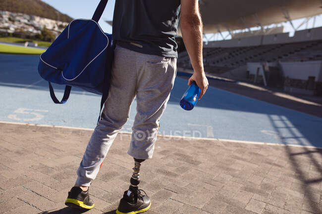 Sección media del atleta masculino caucásico con la pierna protésica de pie en el campo de deportes. concepto de deporte paralímpico - foto de stock