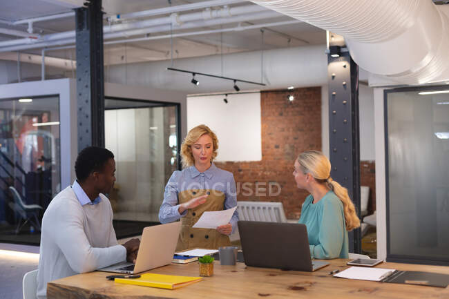 Team of diverse office colleagues discussing together over a document at modern office. business, professionalism, office and teamwork concept — Stock Photo