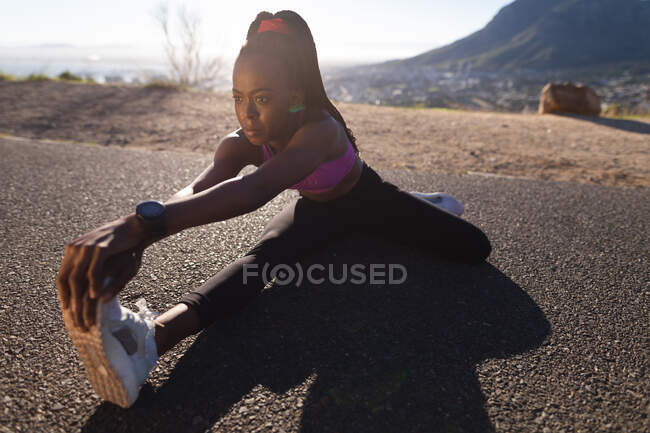 Apto mulher afro-americana que se estende no chão, exercitando-se no campo. estilo de vida ativo saudável e aptidão ao ar livre. — Fotografia de Stock