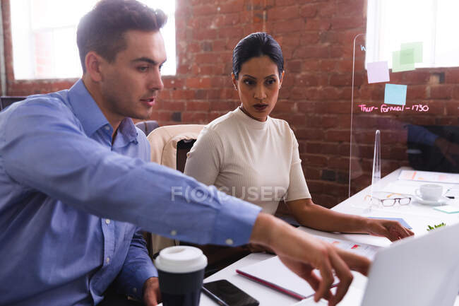 Различные коллеги мужского и женского пола обсуждают за ноутбуком в современном офисе. бизнес, профессионализм, концепция офиса и командной работы — стоковое фото