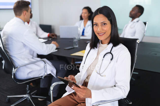 Ritratto di dottoressa afroamericana sorridente seduta su una sedia in sala riunioni. concetto di assistenza sanitaria e professionalità — Foto stock