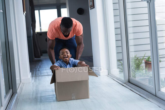 African american father and son, playing together and smiling. at home in isolation during quarantine lockdown. — Stock Photo