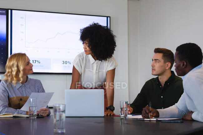 Equipo de diversos colegas masculinos y femeninos discutiendo juntos en la sala de reuniones de la oficina. negocio, profesionalidad, concepto de oficina y trabajo en equipo - foto de stock
