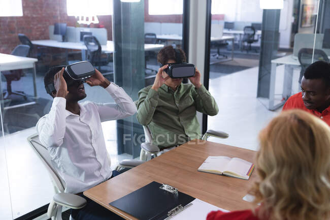 Due diversi colleghi d'ufficio maschili che indossano auricolari VR nella sala riunioni in ufficio. business, professionalità, ufficio e concetto di lavoro di squadra — Foto stock