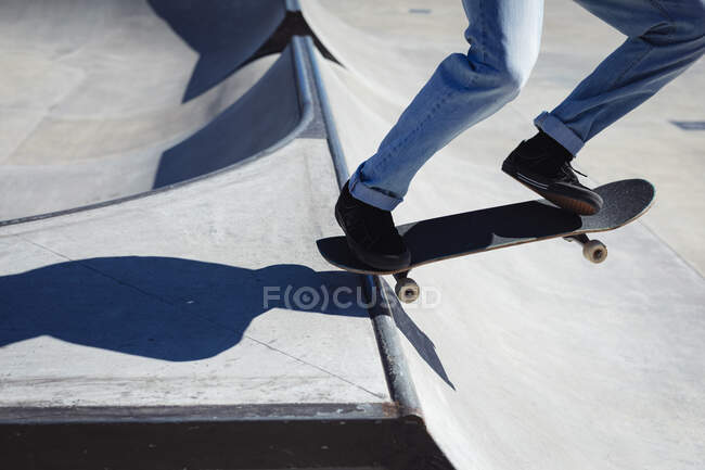 Sección baja de skate de hombre en un día soleado. pasando el rato en skatepark urbano en verano. - foto de stock
