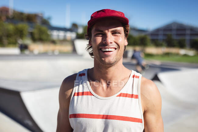 Retrato de homem caucasiano sorrindo para a câmera no dia ensolarado. sair no parque de skate urbano no verão. — Fotografia de Stock