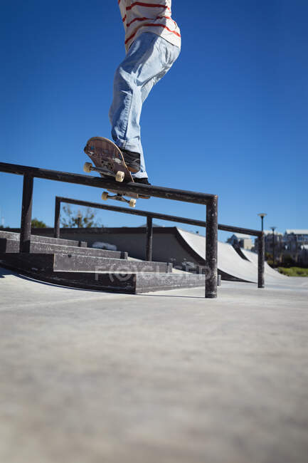 Niedriger Abschnitt der Skateboarding-Mann auf Handlauf an sonnigen Tag. Abhängen im städtischen Skatepark im Sommer. — Stockfoto