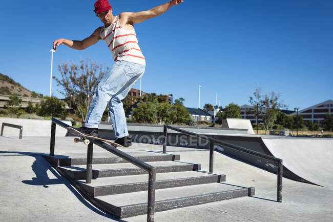 Homme caucasien skateboard sur la main courante par une journée ensoleillée. traîner à skatepark urbain en été. — Photo de stock