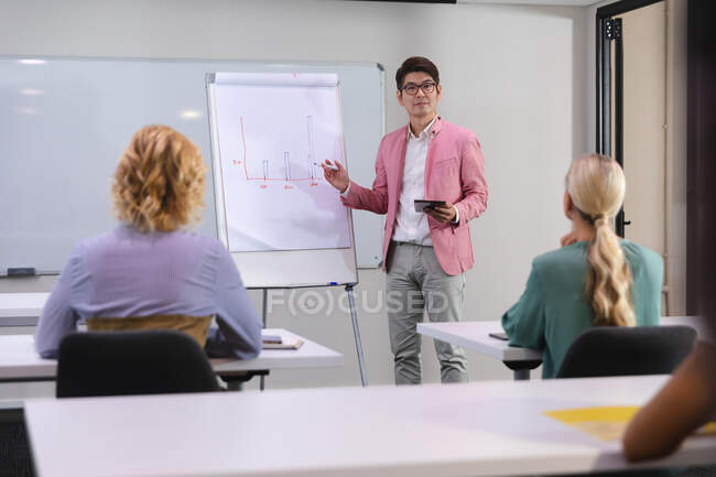 Азиатский мужчина делает презентацию своим коллегам в конференц-зале в офисе. бизнес, профессионализм, концепция офиса и командной работы — стоковое фото