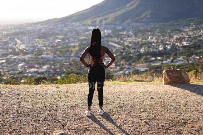 Ajuste mujer afroamericana admirando la vista durante el ejercicio en el campo. estilo de vida activo saludable y fitness al aire libre. - foto de stock