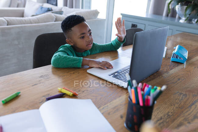 Garçon afro-américain en classe scolaire en ligne, utilisant un ordinateur portable à la maison en isolement pendant le confinement en quarantaine. — Photo de stock
