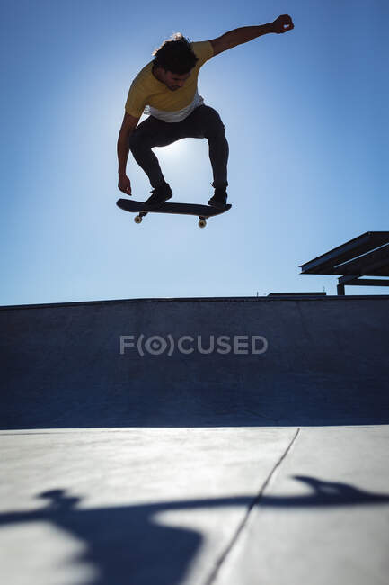 Homme caucasien sautant et skateboard sur une journée ensoleillée. traîner à skatepark urbain en été. — Photo de stock