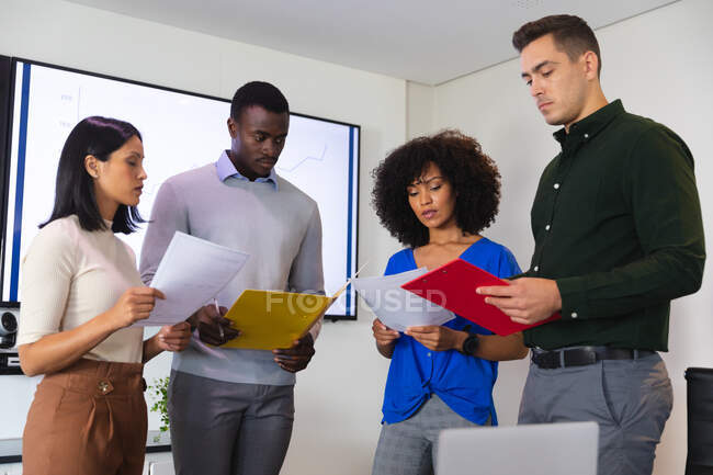 Team of diverse male and female office colleagues holding documents in meeting room at office. business, professionalism, office and teamwork concept — Stock Photo