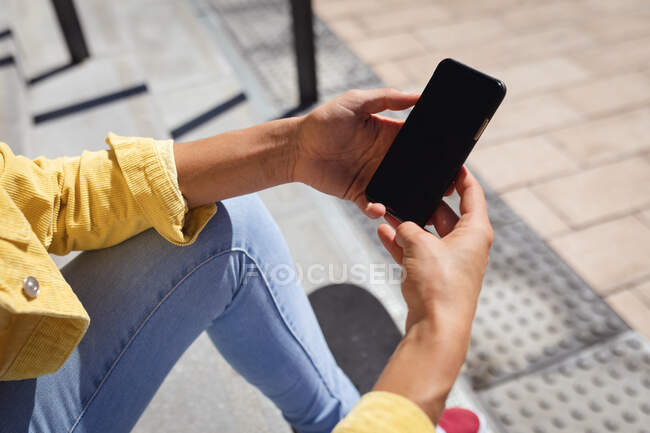Close up de mulher caucasiana sentado em escadas e usando smartphone. sair no parque de skate urbano no verão. — Fotografia de Stock