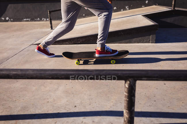 Low section of woman skateboarding in the sun. hanging out at an urban skatepark in summer. — Stock Photo