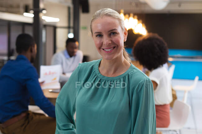 Ritratto di donna caucasica sorridente mentre si trova in un ufficio moderno. business, professionalità e concetto di ufficio — Foto stock