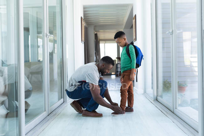 African american father and son helping with dressing up. at home in isolation during quarantine lockdown. — Stock Photo