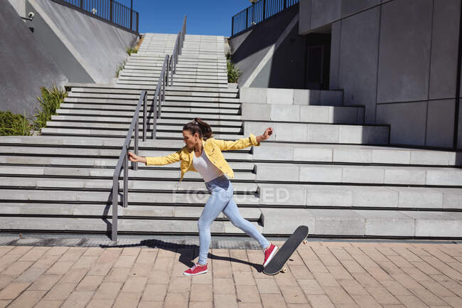 Caucasian woman falling off skateboard next to stairs. hanging out at urban skatepark in summer. — Stock Photo