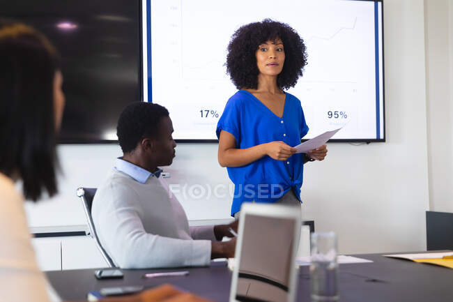 Femme afro-américaine donnant une présentation à ses collègues de bureau dans la salle de réunion au bureau. concept d'entreprise, de professionnalisme, de bureau et de travail d'équipe — Photo de stock
