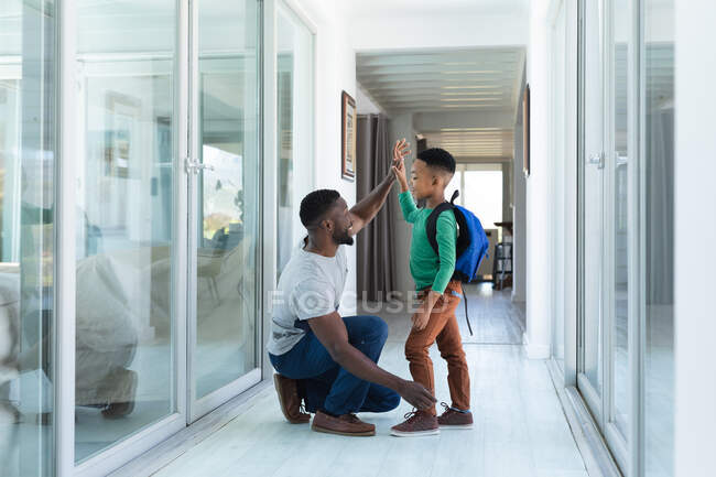 Африканский американец отец и сын улыбаются и дают пять. в доме в изоляции во время карантинной изоляции. — стоковое фото