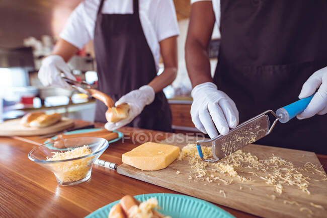 Midsection of mixed race woman grating cheese behind counter in food truck. independent business and street food service concept. — Stock Photo