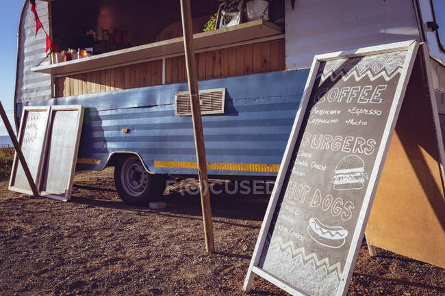 General view of food truck and menu board by seaside on sunny day. independent business and street food service concept. — Stock Photo