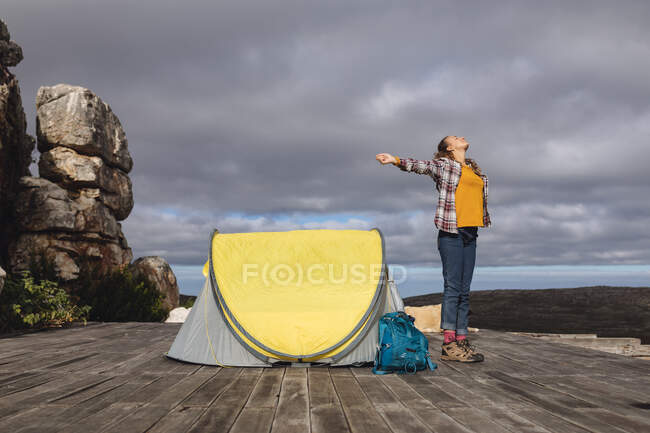 Счастливая белая женщина кемпинг, стоя снаружи палатка на палубе горы с распростертыми руками. здоровый образ жизни, вне сети и близко к природе. — стоковое фото