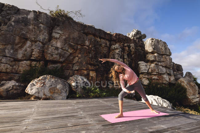 Щаслива біла жінка практикує йогу, стоячи на палубі, що тягнеться в сільській місцевості. здорове життя, поза мережею і близькість до природи . — стокове фото