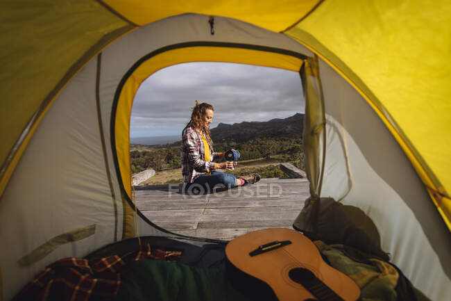 Кавказская женщина разбила лагерь, сидела снаружи палатки на горной палубе и наливала кофе. здоровый образ жизни, вне сети и близко к природе. — стоковое фото