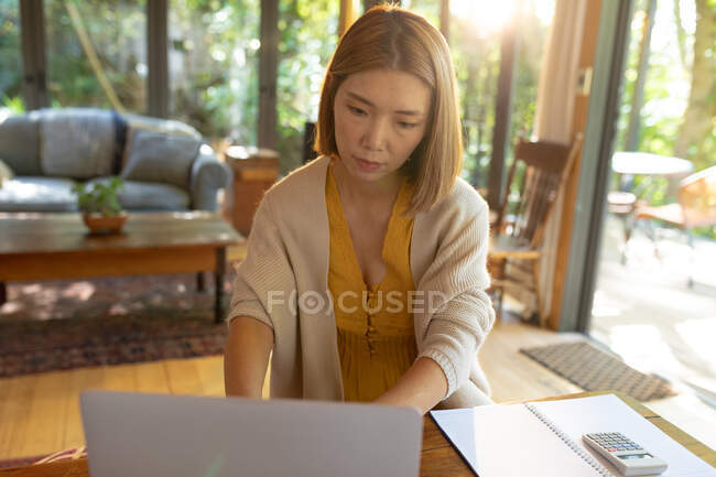 Asian woman using laptop sitting at table, working from home. at home in isolation during quarantine lockdown. — Stock Photo
