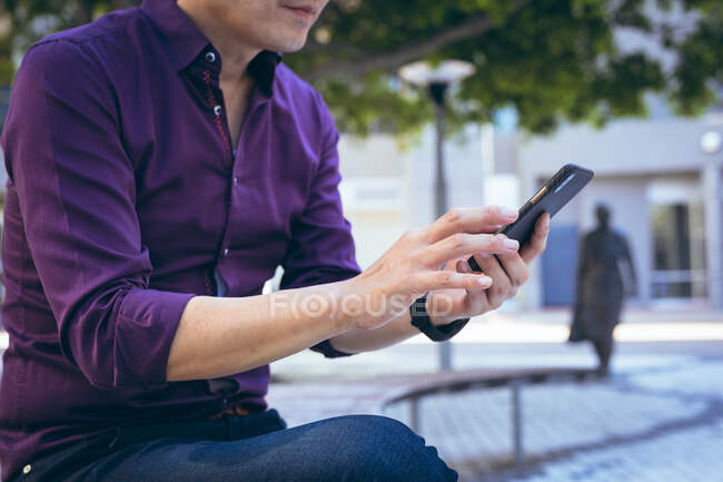 Midsection de hombre de negocios asiático usando teléfono inteligente en la calle de la ciudad. nómada digital en concepto de ciudad. - foto de stock
