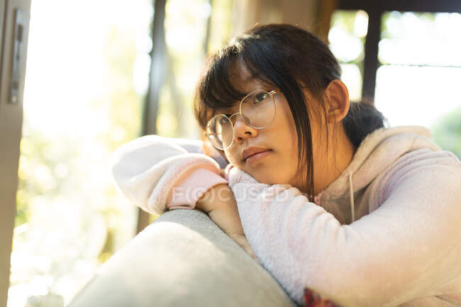 Портрет дбайливої азійської дівчини в окулярах, що сидить на дивані. вдома в ізоляції під час карантину.. — стокове фото