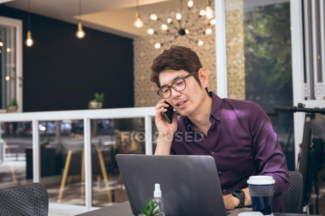 Asian businessman using smartphone and laptop in hotel lobby. business travel, digital nomad on the go out and about in city concept. — Stock Photo