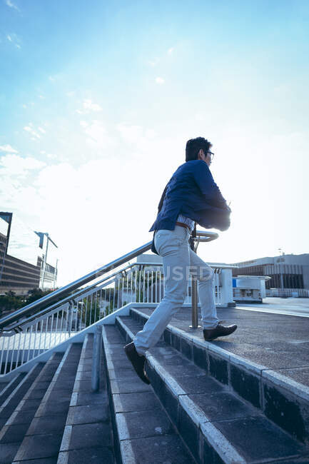 Asian businessman walking up steps in city street. businessman out and about in city concept. — Stock Photo