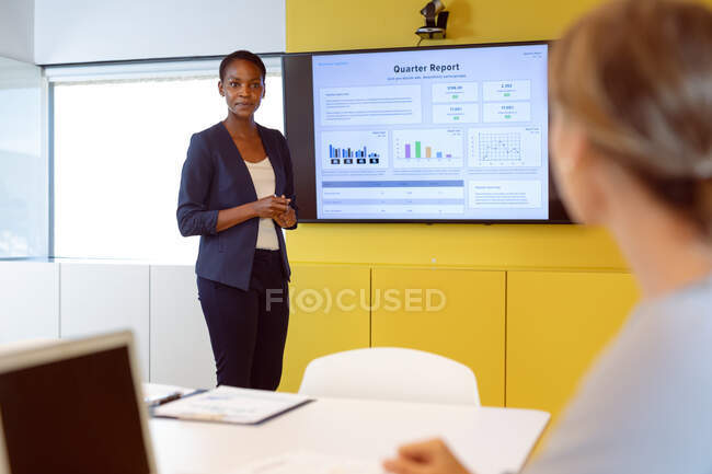 Mulher de negócios afro-americana fazendo apresentação na frente da mulher caucasiana. negócio criativo independente em um escritório moderno. — Fotografia de Stock