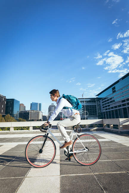 Hombre de negocios asiático montar en bicicleta en la calle de la ciudad con edificios modernos en el fondo. hombre de negocios fuera y alrededor en concepto de ciudad. - foto de stock