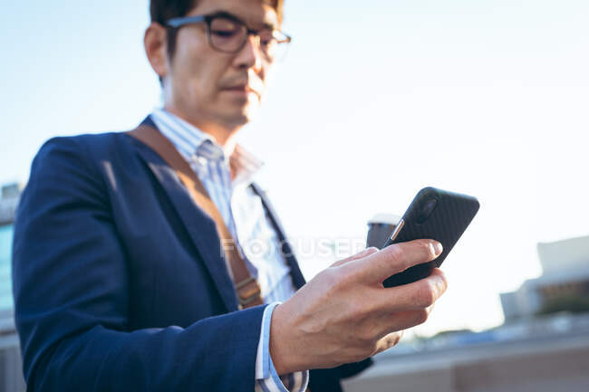 Midsection азиатского бизнесмена, использующего смартфон на городской улице. цифровая реклама и концепция города. — стоковое фото