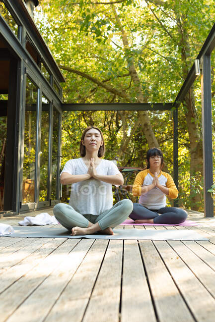 Asian mother and her daughter practicing yoga on terrace in garden. at home in isolation during quarantine lockdown. — Stock Photo