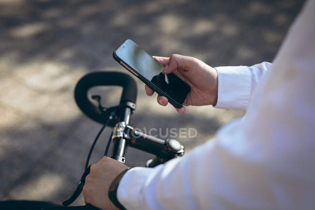 Midsection de homem de negócios usando smartphone de pé com bicicleta na rua da cidade. nômade digital para fora e sobre no conceito da cidade. — Fotografia de Stock