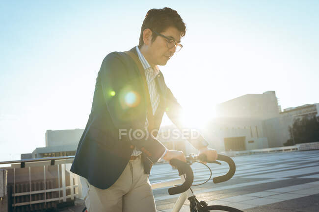 Sezione centrale di uomo d'affari asiatico a piedi con la bicicletta in strada della città. uomo d'affari in giro per la città concetto. — Foto stock