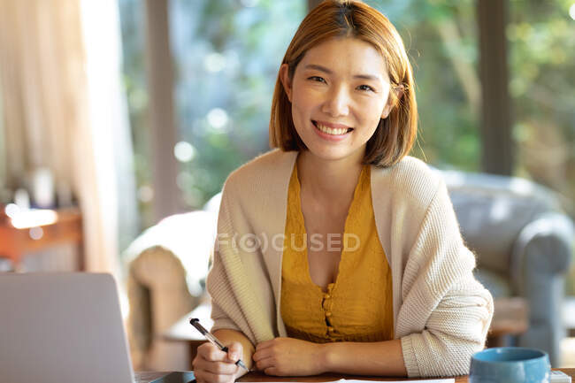 Porträt einer lächelnden Asiatin, die von zu Hause aus arbeitet. Zuhause in Isolation während der Quarantäne. — Stockfoto