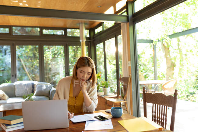 Asian woman using laptop and writing, working from home. at home in isolation during quarantine lockdown. — Stock Photo