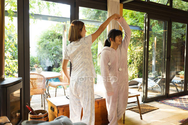 Madre asiática y su hija bailando en la sala de estar. en casa en aislamiento durante el bloqueo de cuarentena. - foto de stock