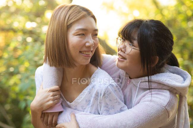 Portrait de femme asiatique souriante avec sa fille embrassant dans le jardin. à domicile en isolement pendant le confinement en quarantaine. — Photo de stock