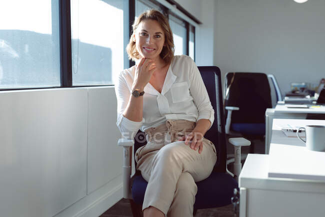 Smiling caucasian businesswoman sitting at desk at work. independent creative business at a modern office. — Stock Photo