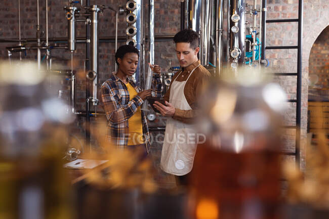 Різні чоловіки і жінки-працівниці обговорюють цифровий планшет в джин-винокурні. виробництво алкоголю та концепція фільтрації — стокове фото